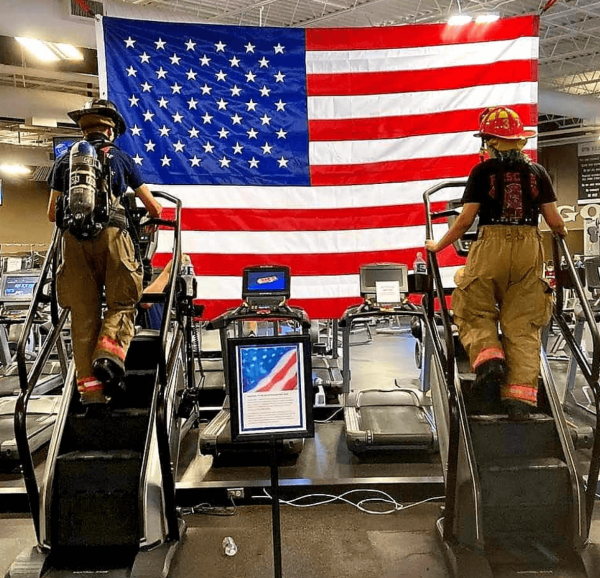 firefighters on stepping machine in front of American flag