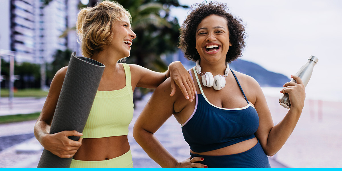 Two people in workout gear smiling holding workout equipment
