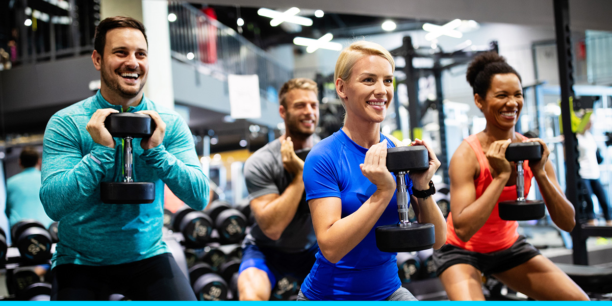 a group of 4 people squatting and holding dumbbells
